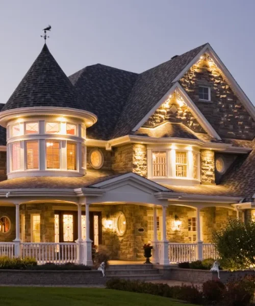 An elegant gray and white house with the lights on.
