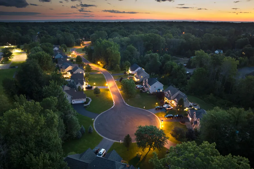 A lit up suburban houses in the sundown.